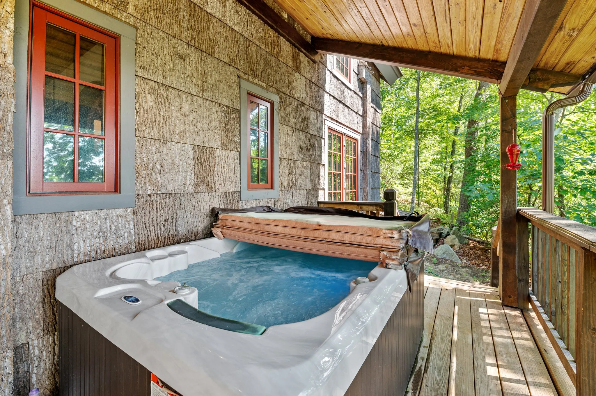 Deck Hot Tub Outdoor hot tub on wooden deck surrounded by forest canopy with red window frames