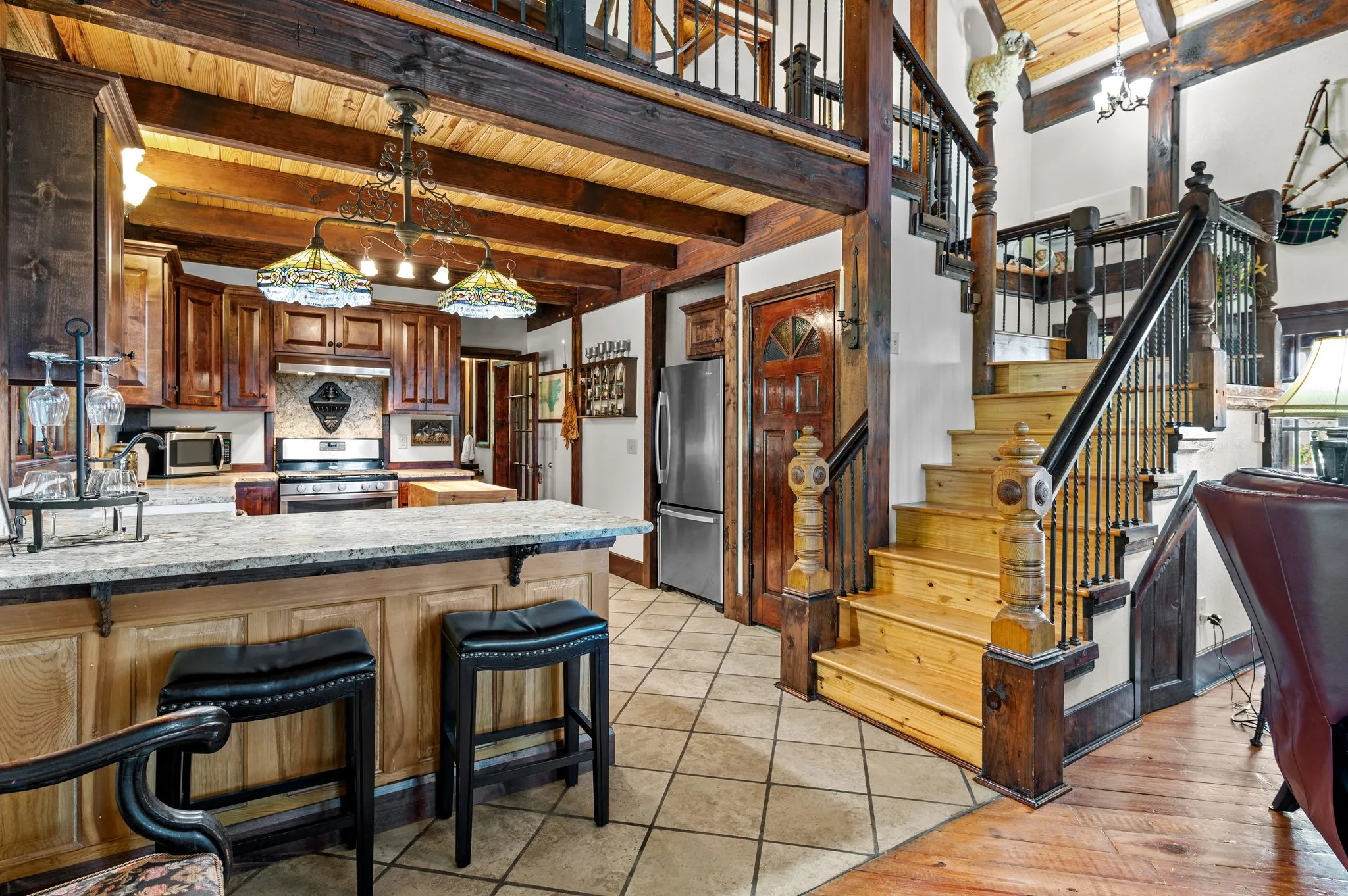 Kitchen Gourmet kitchen with custom wood cabinetry, island, bar stools, and open staircase