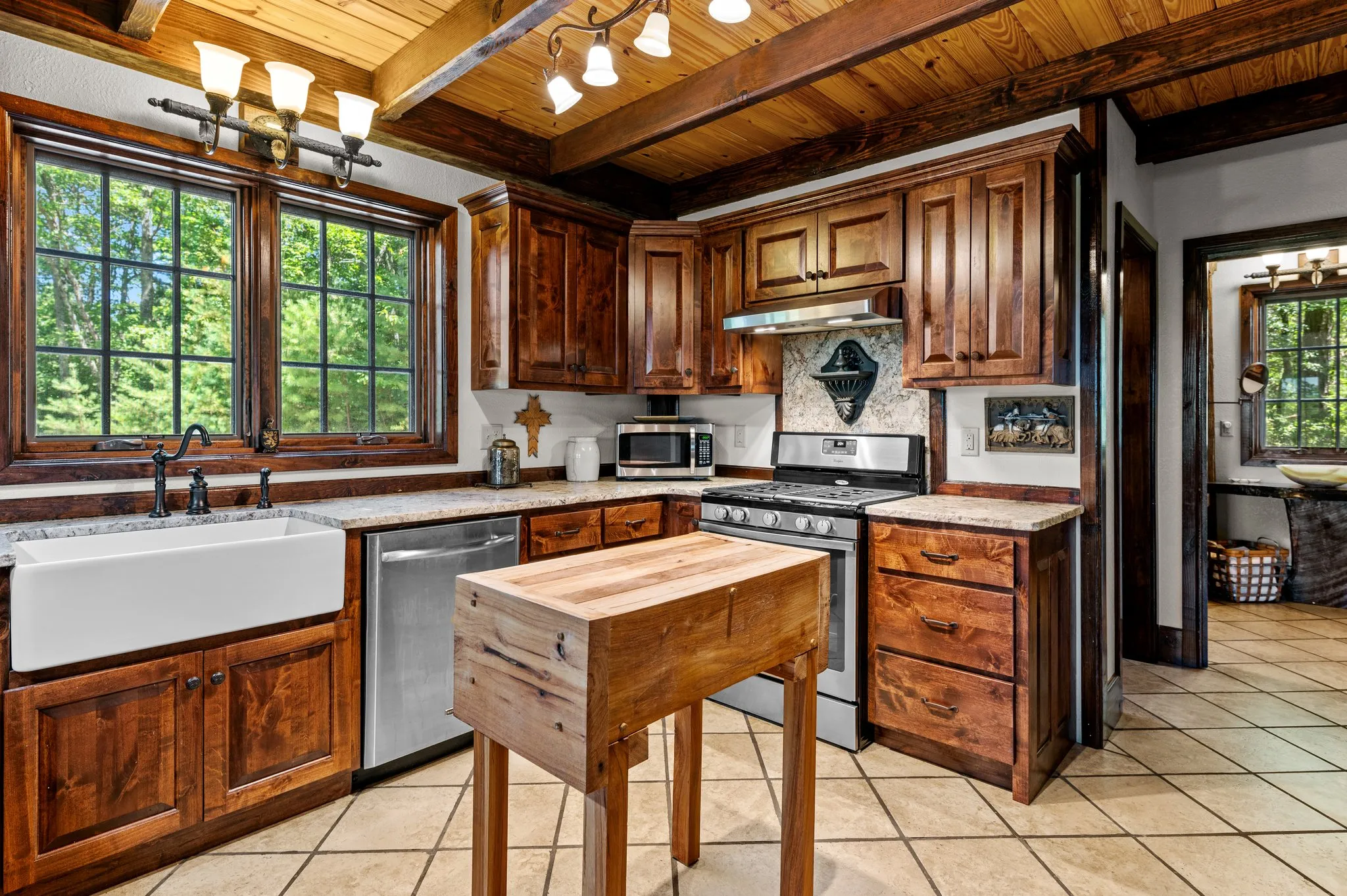 Chef's Kitchen Modern kitchen with rustic wood cabinets, apron sink, stainless appliances, and island workspace