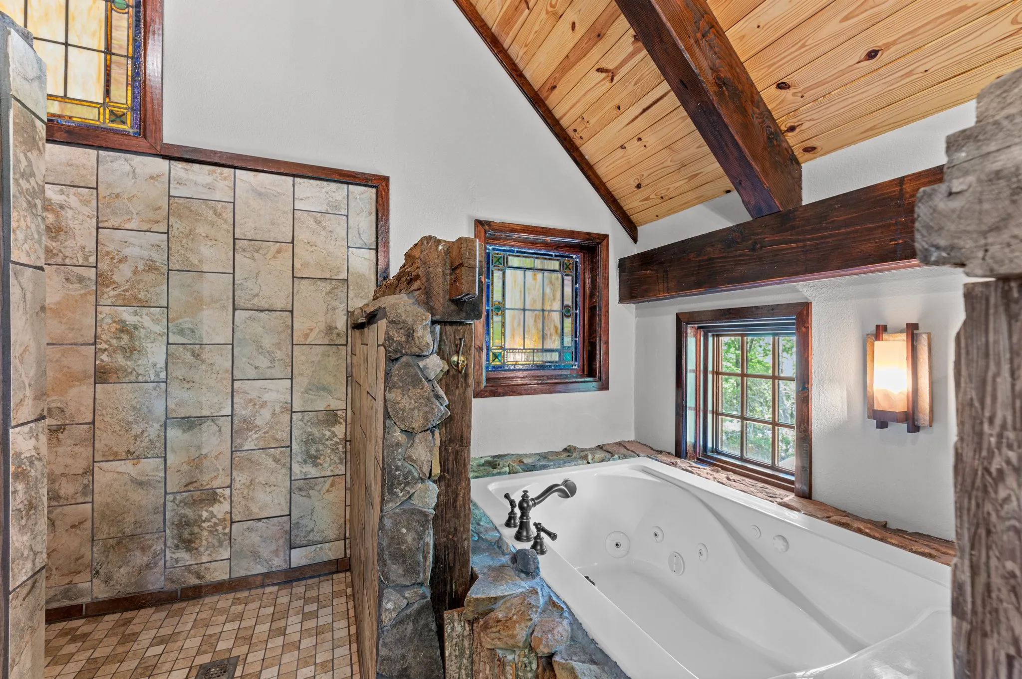Master Bathroom Luxurious master bathroom with jetted tub, stained glass windows, stone accents, and timber beam ceiling