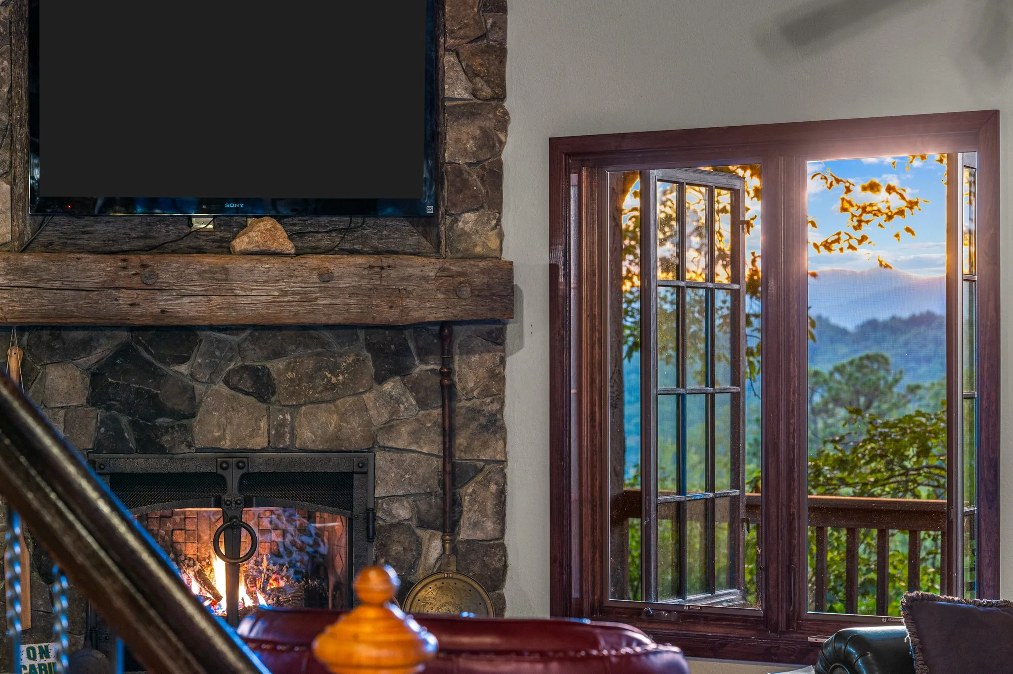 Fireplace Lounge Cozy seating area with working stone fireplace, TV, and glass doors opening to panoramic mountain view