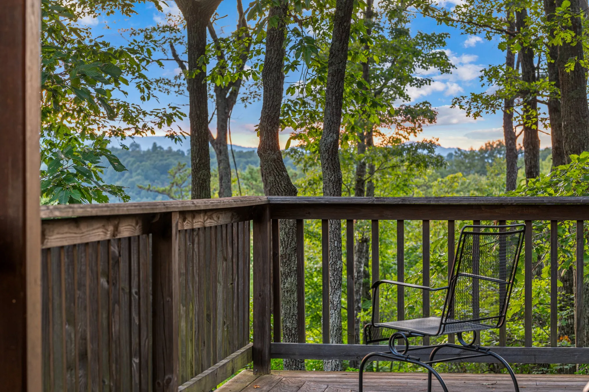 Deck Mountain View Peaceful wooden deck with chairs overlooking layered mountain ranges through forest trees