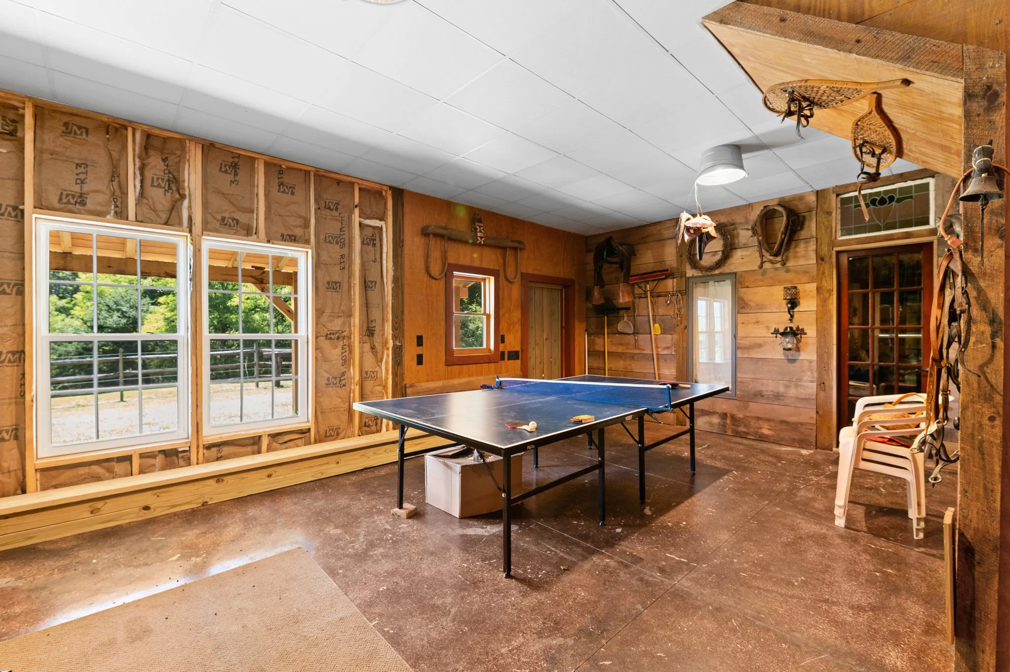 Barn game room with ping pong table, vintage farm tools, and sliding glass doors to deck